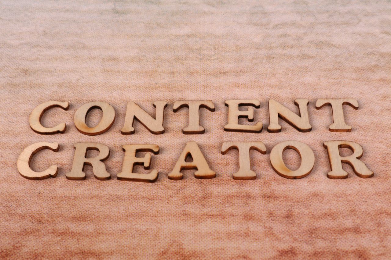 Wooden letters spelling Content Creator arranged on a textured fabric background.